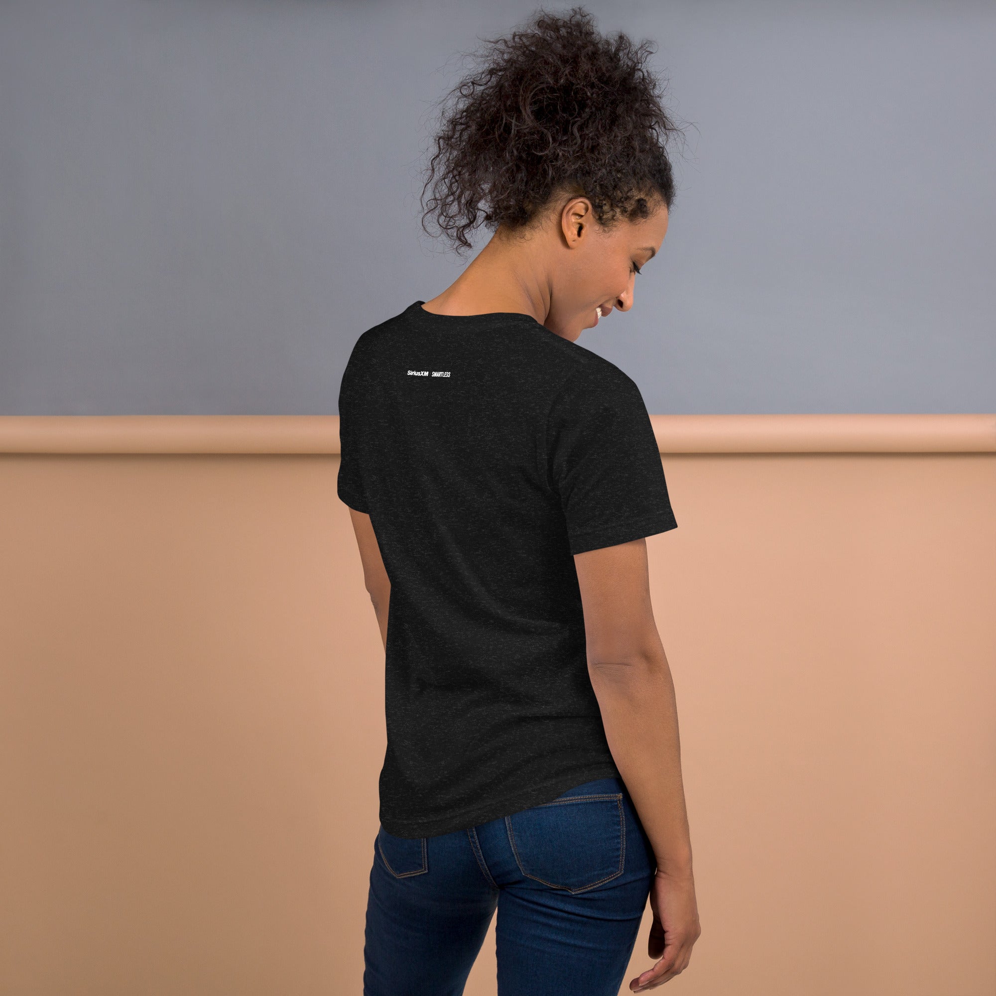 A woman seen from behind wearing a black heather T-shirt, displaying the white printed 'SiriusXM' and 'SMARTLESS' logos at the top center of the back.