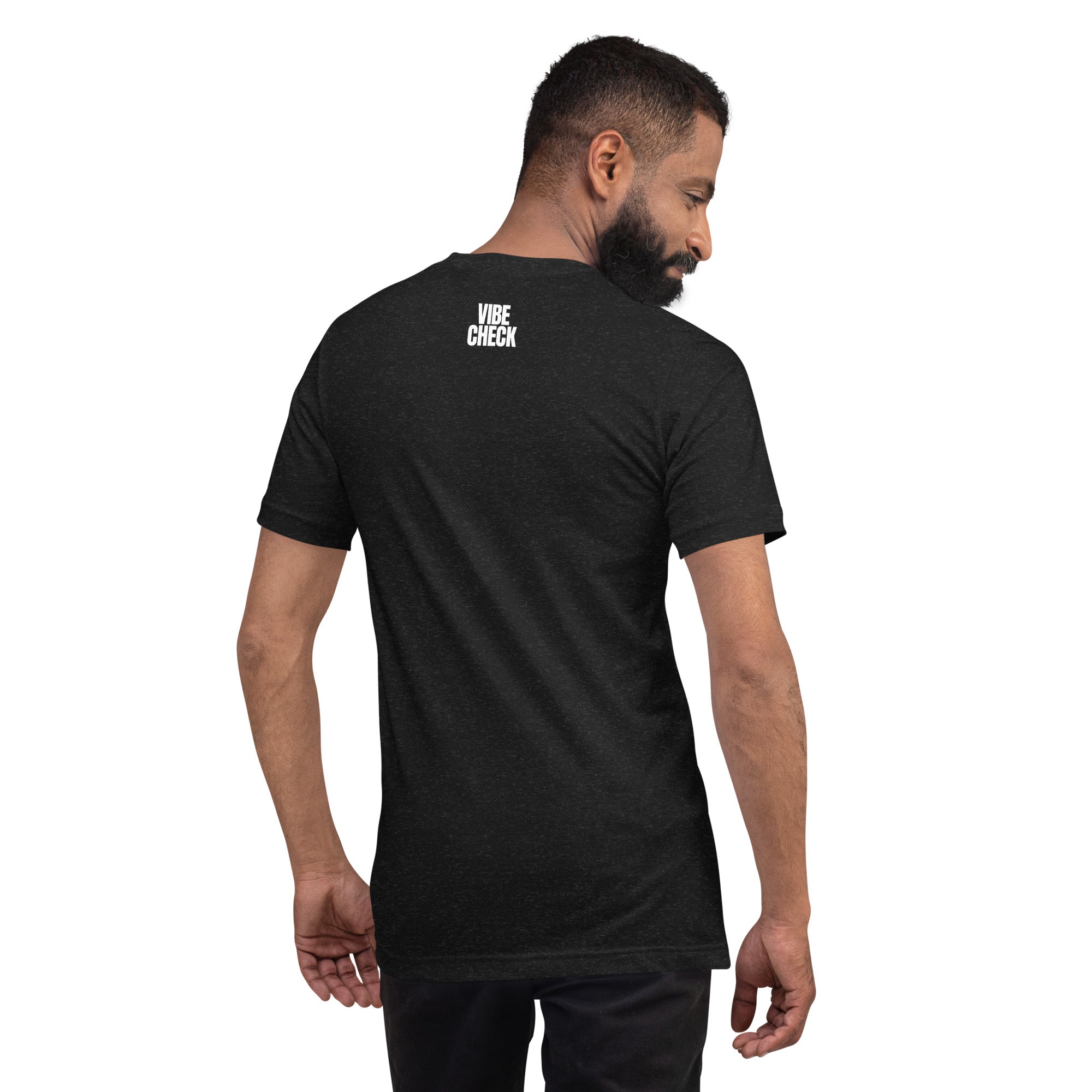 A man wearing a black heather t-shirt is shown from behind, turning slightly to his left. The back of the shirt features the phrase 'VIBE CHECK' in small white capital letters printed just below the neckline. The man has a short beard and is wearing black pants, standing against a plain white background.
