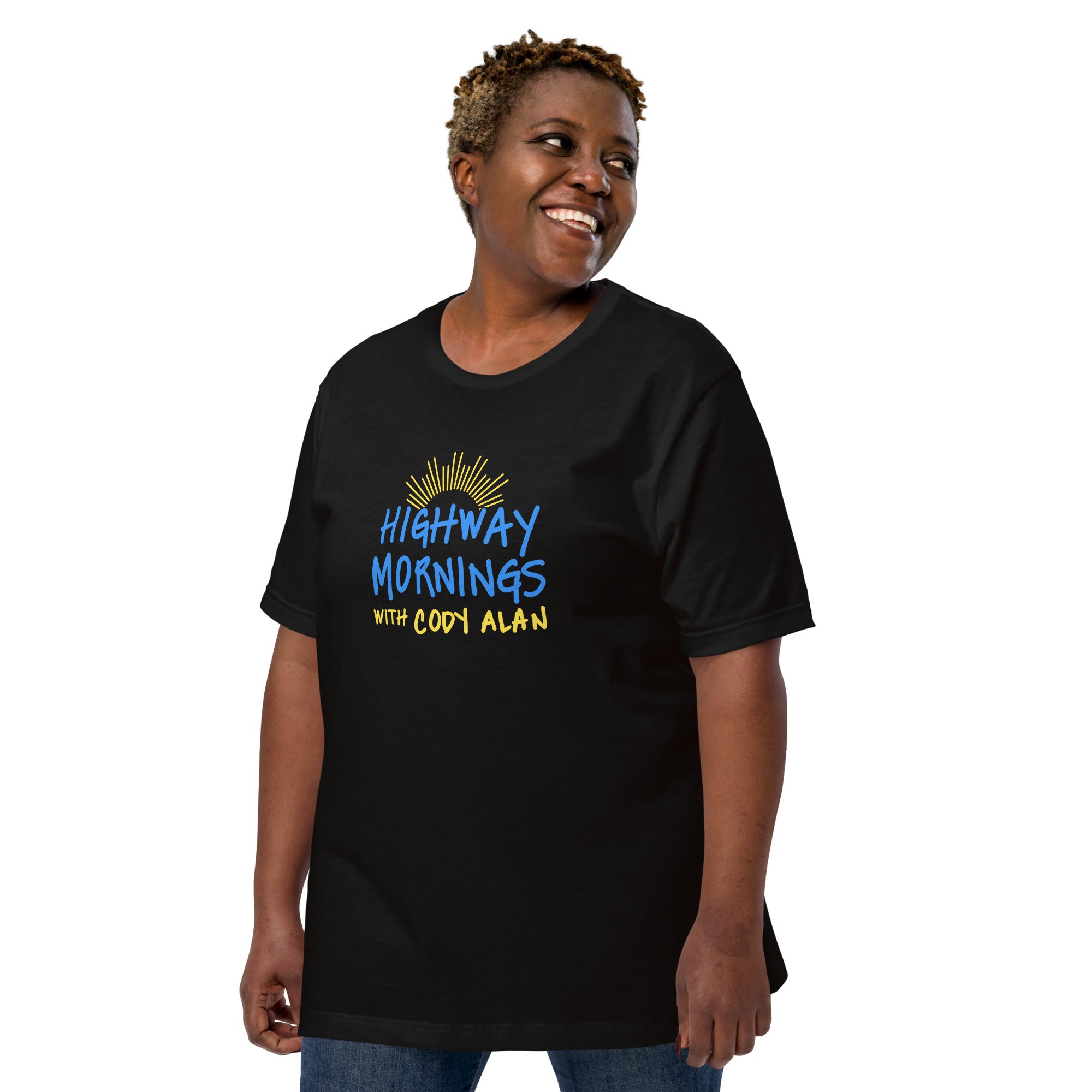 A smiling woman wearing a black t-shirt featuring the phrase 'HIGHWAY MORNINGS WITH CODY ALAN' in blue and yellow text with a sunburst graphic above the design.