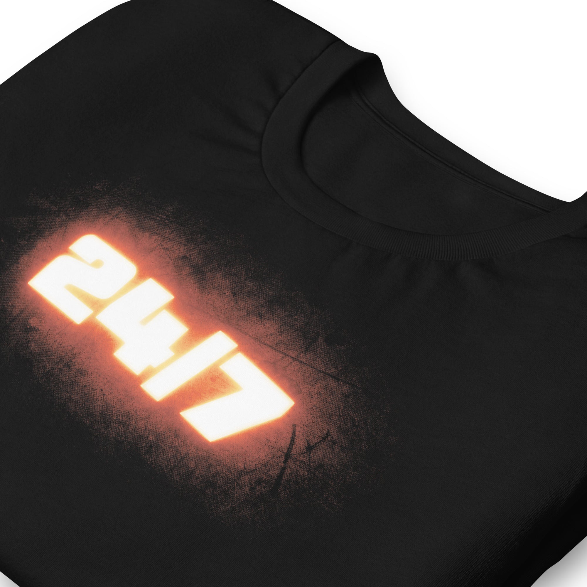 Close-up of black t-shirt fabric showing the front graphic design ‘24/7’ in bold white numbers with a glowing orange effect and a soft, distressed texture around the edges.