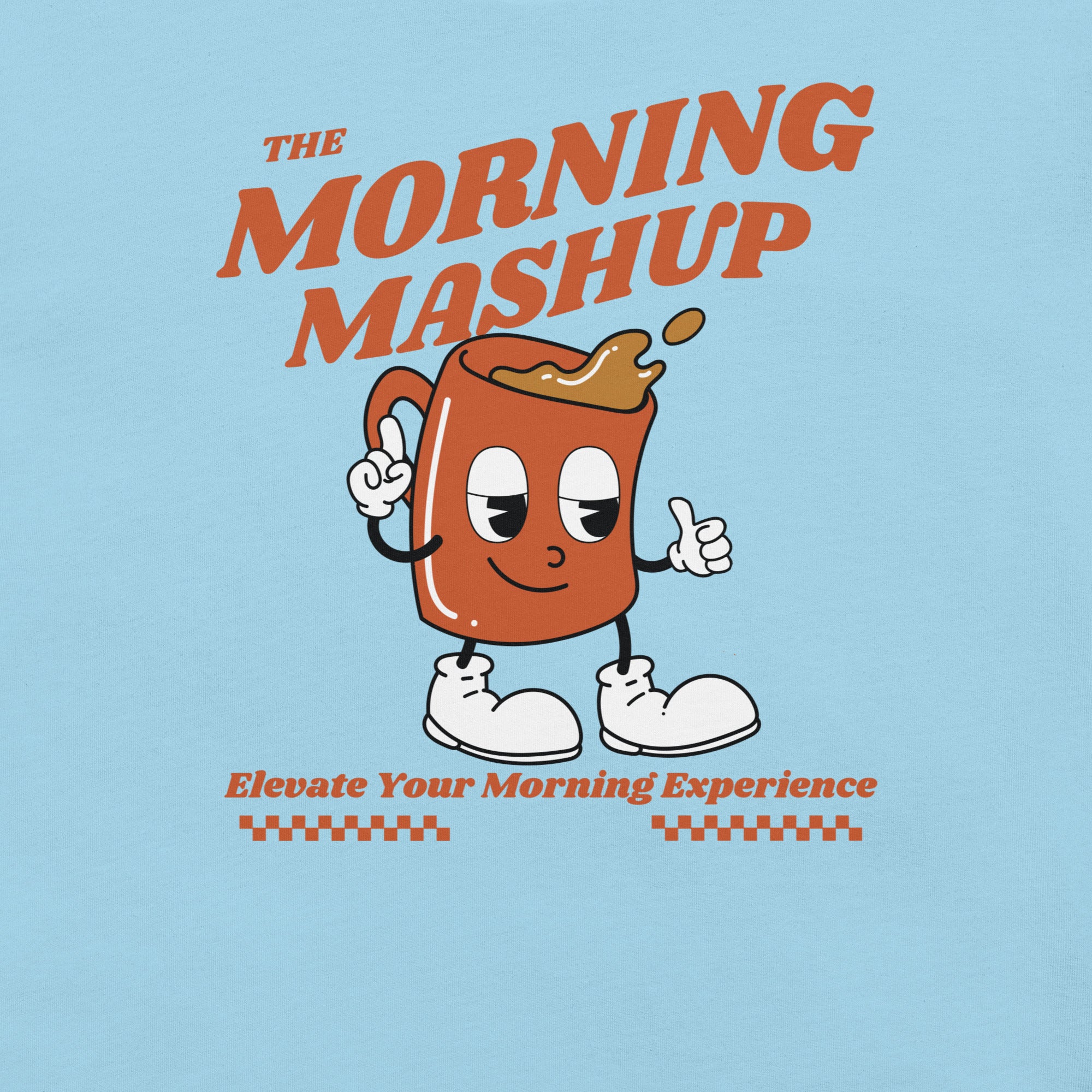 Detailed view of the cartoon coffee mug graphic on a light blue T-shirt. The orange mug character has expressive eyes, white gloved hands pointing out, walking in white sneakers while giving a thumbs up. Above the image is the bold orange text 'THE MORNING MASHUP,' and below it says 'Elevate Your Morning Experience' with dark orange checkered underline details.