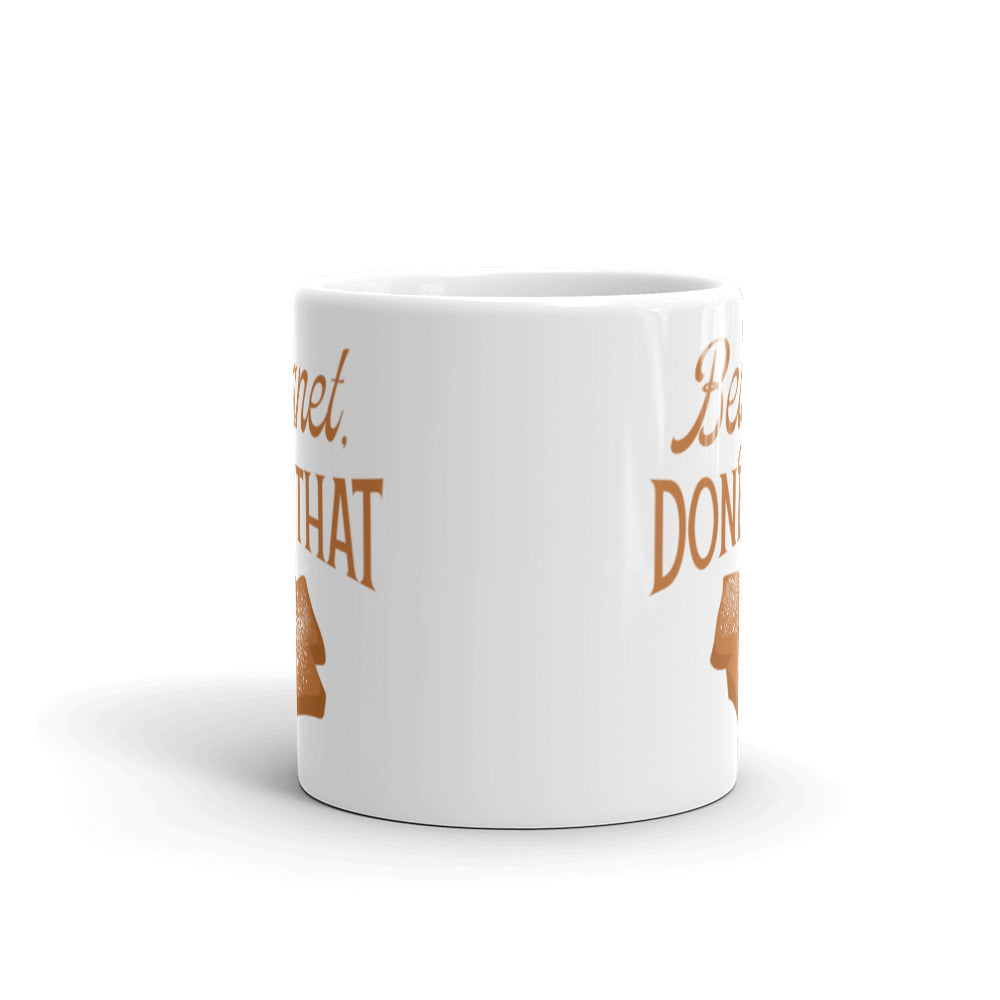 Side view of white mug partially featuring front and back text and illustrations.