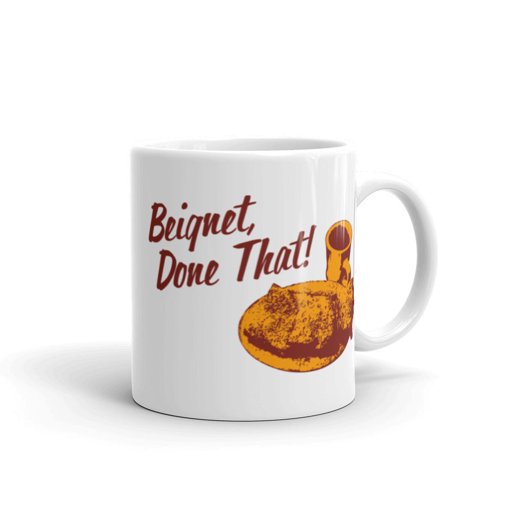 Coffee mug with a beignet and cup of coffee graphic and the text 'Beignet, Done That!' with the handle on the right.