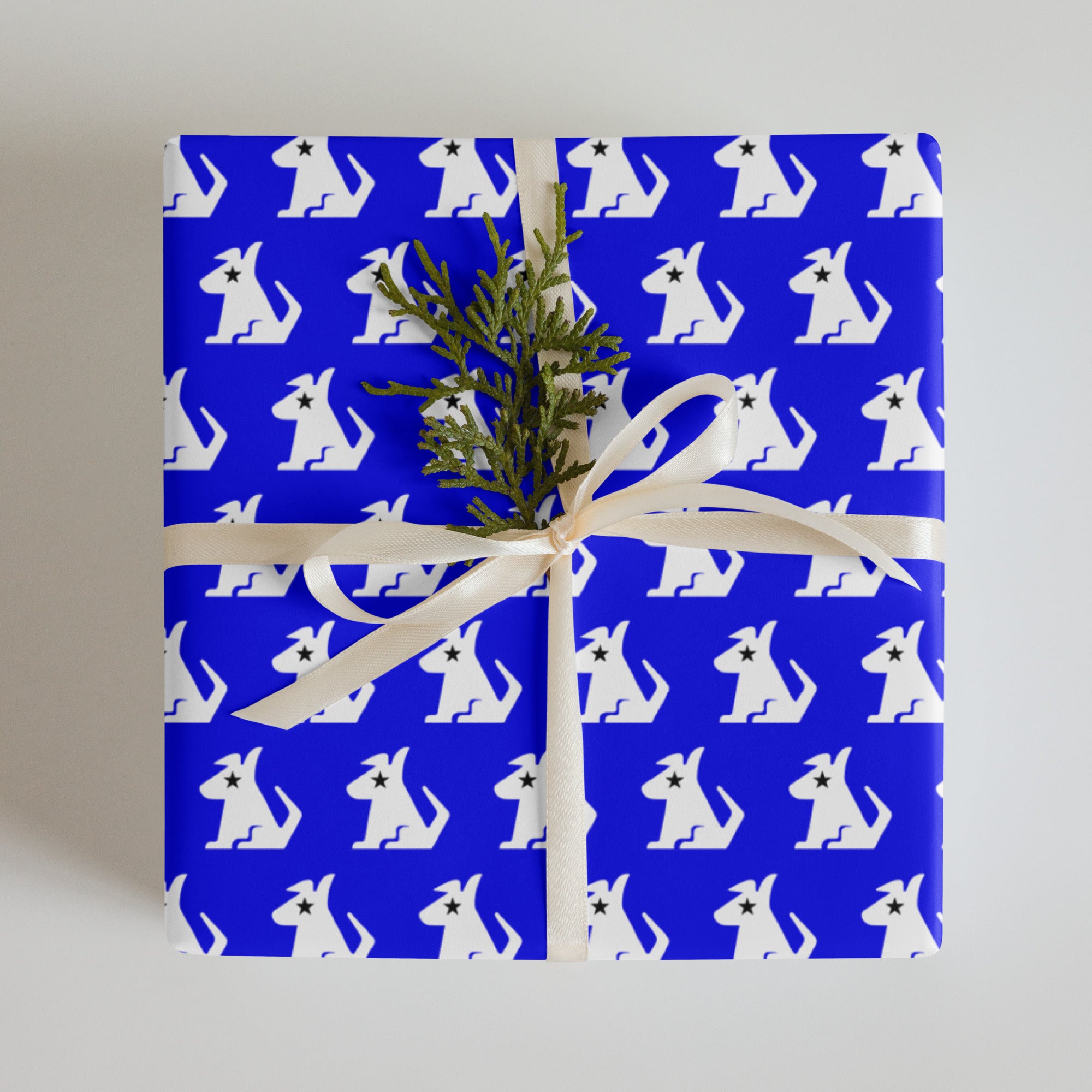 A beautifully wrapped gift in blue paper featuring white dog patterns, tied with a ribbon and adorned with a sprig.